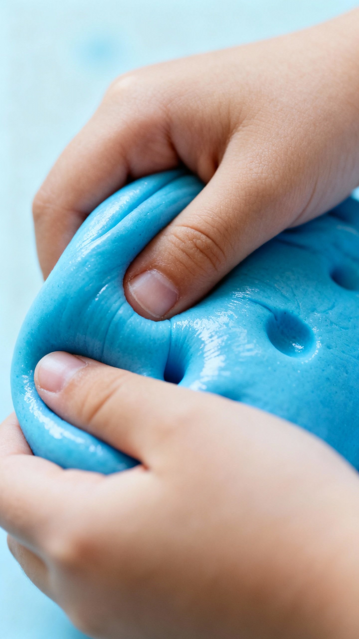 Closeup of child’s hands squeezing blue therapy putty