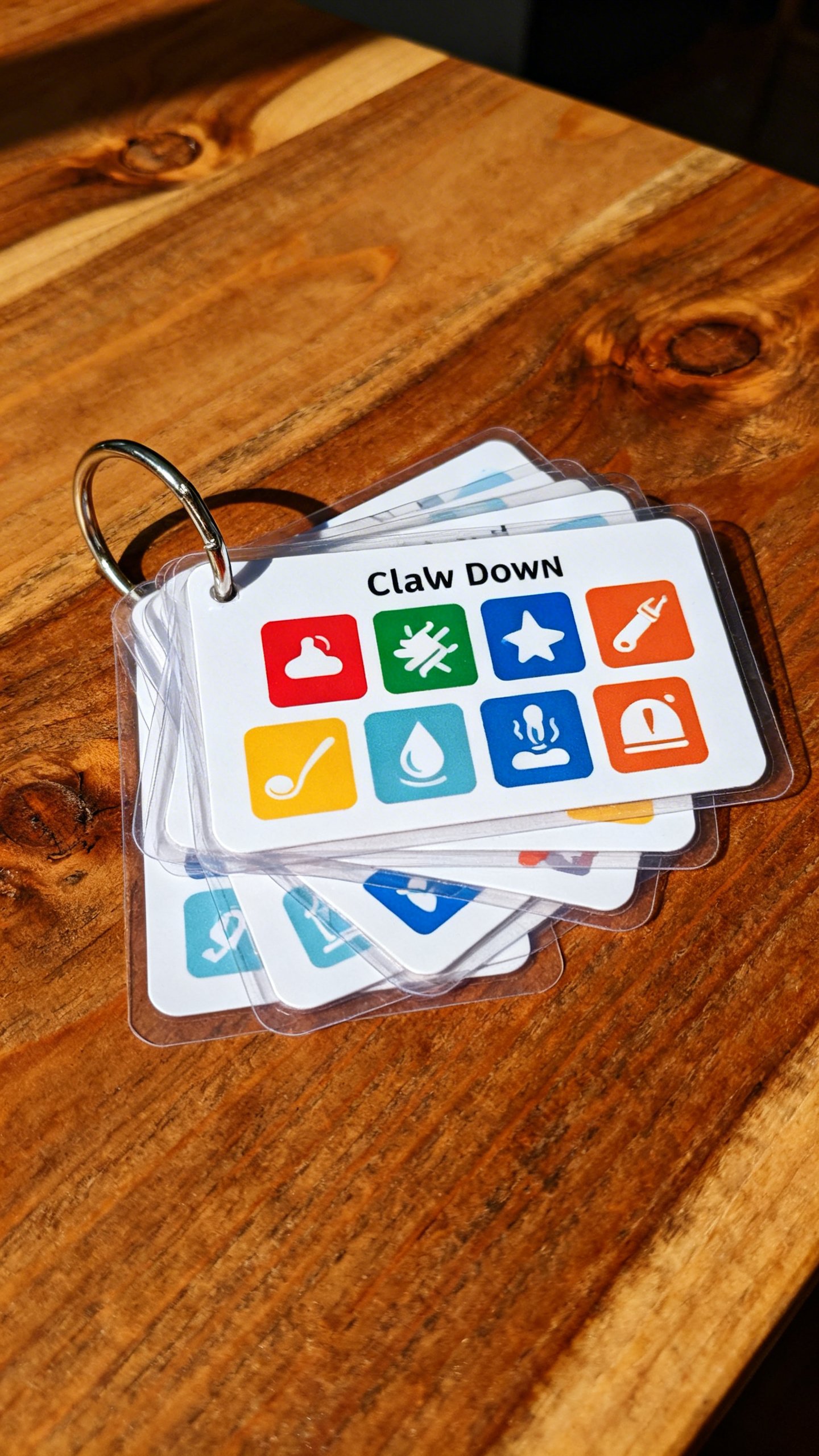 Closeup of laminated calm-down cards on binder ring, colorful icons, high-contrast, wooden table
